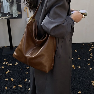Détail d'un sac hobo en cuir marron foncé avec surpiqûres contrastées et boucle dorée