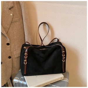 Detail of black suede pillow bag with brown leather handles and golden metal hardware