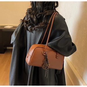 Détail du sac bowling en cuir caramel avec pendentif tressé et fermeture éclair métallique