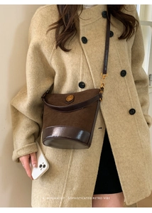 Detail of vintage brown suede bucket bag with gold hardware and leather strap