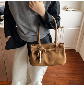 Detail of vintage brown bucket bag with smooth matte finish and colorful beaded charm