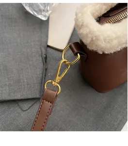 Détail du sac en daim marron avec bordure en peluche blanche et crochets dorés
