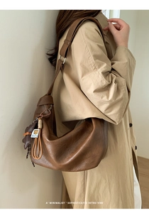 Detail of brown retro leather dumpling bag with textured finish and side charms