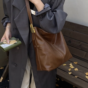 Détail du sac seau en cuir marron avec surpiqûres blanches et boucle en métal doré