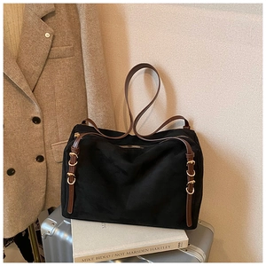 Detail of black suede Boston bag with brown leather strap and gold metal hardware adjustment