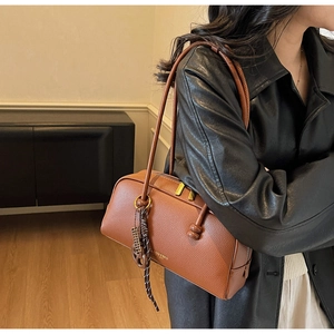 Détail du sac bandoulière en cuir grainé marron avec logo doré et bijou de sac