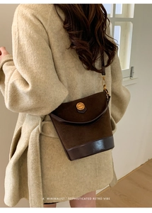 Detailed back view of vintage brown suede bucket bag with round metal hardware detail