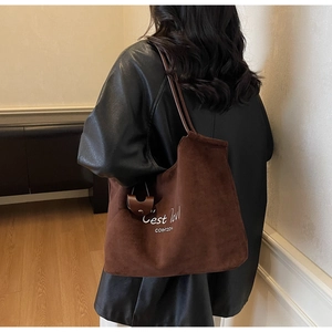Detail of dark brown suede tote bag with white embroidery and fine shoulder straps