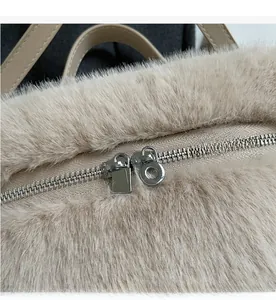 Details des glatten silbernen Metallreißverschlusses am beigen Plüschrucksack