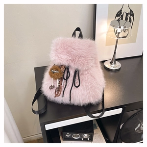Detail eines rosa Plüschrucksacks mit süßem Löwenanhänger und schwarzen Trägern