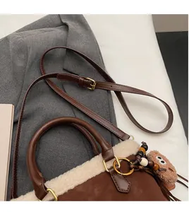 Détail du sac seau en peluche avec bandoulière réglable et accessoire de charme