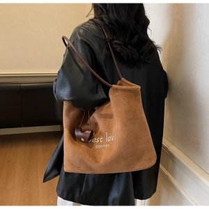 Detail of brown suede tote bag with white lettering embroidery and detachable coin purse