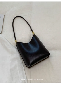 Close-up of retro minimalist dark leather hobo bag with sleek golden metal hardware