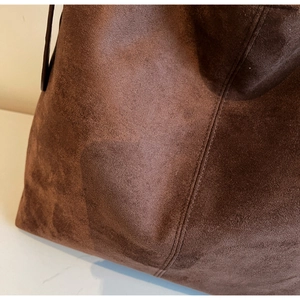 Close-up of dark brown vintage suede bucket bag showing fine texture and double stitching