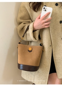Detailed shot of retro suede bucket bag with metal buckle and mixed leather textures