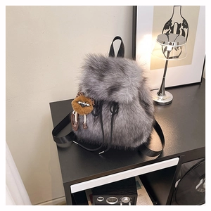 Detailansicht der grauen Kunstfell-Rucksacktasche mit schwarzen Trägern und Anhänger