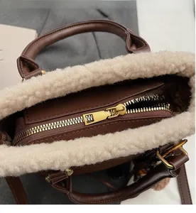 Détail de la fermeture éclair dorée et de la bordure en peluche sur le sac marron