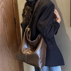 Détail du sac seau en cuir marron vintage avec surpiqûres blanches et boucle dorée