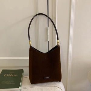 Detail of dark brown suede hobo bag with thin shoulder strap and gold hardware