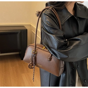 Vue détaillée du cuir grainé marron foncé avec fermeture éclair dorée et pendentif