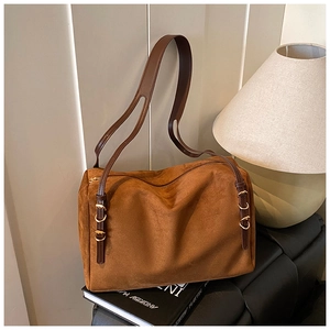 Detail of adjustable leather strap with gold rings on a brown suede pillow tote bag