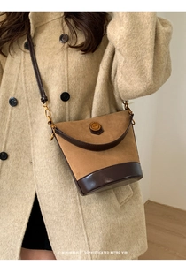 Detail of retro bucket bag in brown suede and leather texture with gold metal plate