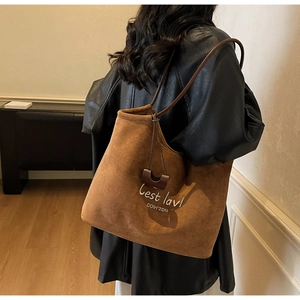 Detail of vintage brown suede tote bag with embroidery on black leather jacket