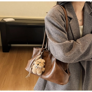 Détail du sac cabas rétro en cuir marron avec un pendentif en peluche pour chien