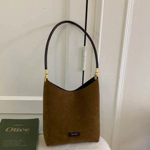 Detail of dark brown suede shoulder bag featuring gold hardware and No Filter label