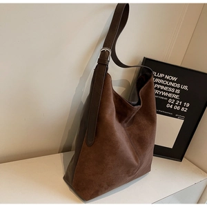 Close-up of vintage brown suede bucket bag with leather strap and silver buckle detail