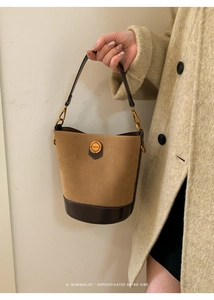 Detail of vintage suede bucket bag with contrast leather trim and golden metal fashion plate