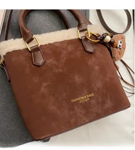 Gros plan d'un sac en daim marron avec bordure en peau lainée et breloque en perles bois