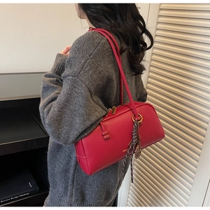 Détail du sac Boston rouge à texture litchi avec zip doré et ruban à pois stylé
