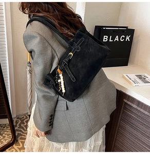 Detail view of black frosted bucket bag with buckle strap and colorful beaded charm
