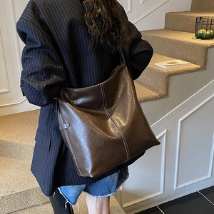 Détail d'un cabas en cuir marron foncé avec coutures blanches contrastées à l'épaule
