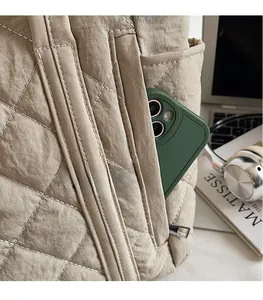 Detail of khaki quilted tote side pocket holding a smartphone with white stitching details