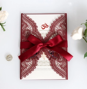Detailed laser cut red lace wedding invitation with a burgundy ribbon and Hindu Om symbol
