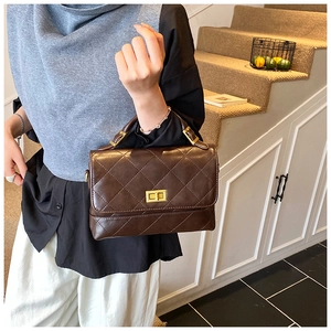 Détail d'un sac à main marron matelassé avec fermoir doré et poignée dans un cadre lifestyle