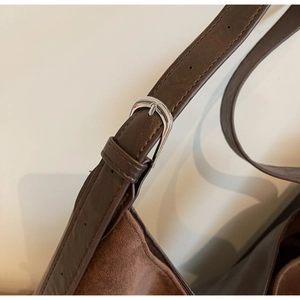 Close-up of dark brown suede bucket bag featuring silver buckle and adjustable strap