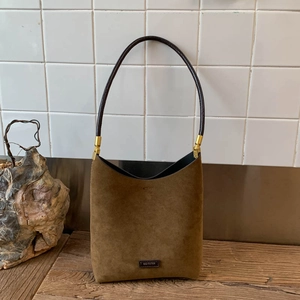Detail of dark brown suede bucket bag with gold hardware and NO FILTER leather tag