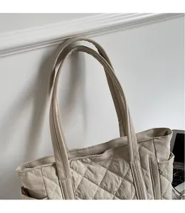 Close-up of quilted khaki tote bag showing padded long shoulder straps and side pocket