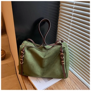 Detail of green faux suede pillow bag featuring brown leather strap and gold hardware accents