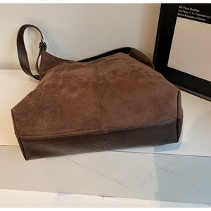 Detail of vintage suede bucket bag showing contrast leather stitching and adjustable strap