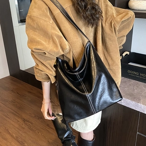 Détail du sac seau en similicuir noir avec surpiqûres blanches contrastées sur le côté
