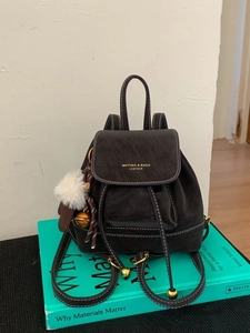 Minimalist leather drawstring backpack with gold hardware and plush charm for travel