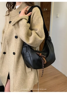 Side view of a large black leather hobo bag with pleated texture on a model