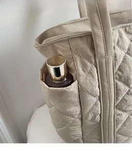 Detailed side pocket of khaki quilted tote bag showing storage for skincare items