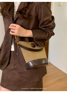 Detail of retro color-block bucket bag with bronze logo and suede texture on model