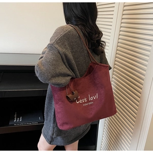 Detailed close-up of large burgundy tote bag with white letter embroidery and shoulder strap