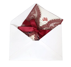 Detail of laser-cut burgundy lace wedding invitation with red silk bow and white envelope